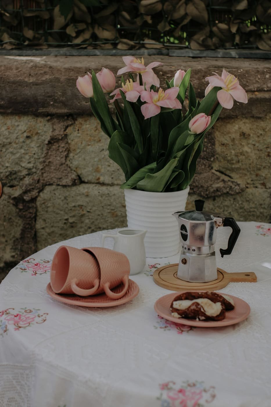 Coffee cups and tulips on a table beside the old stone wall