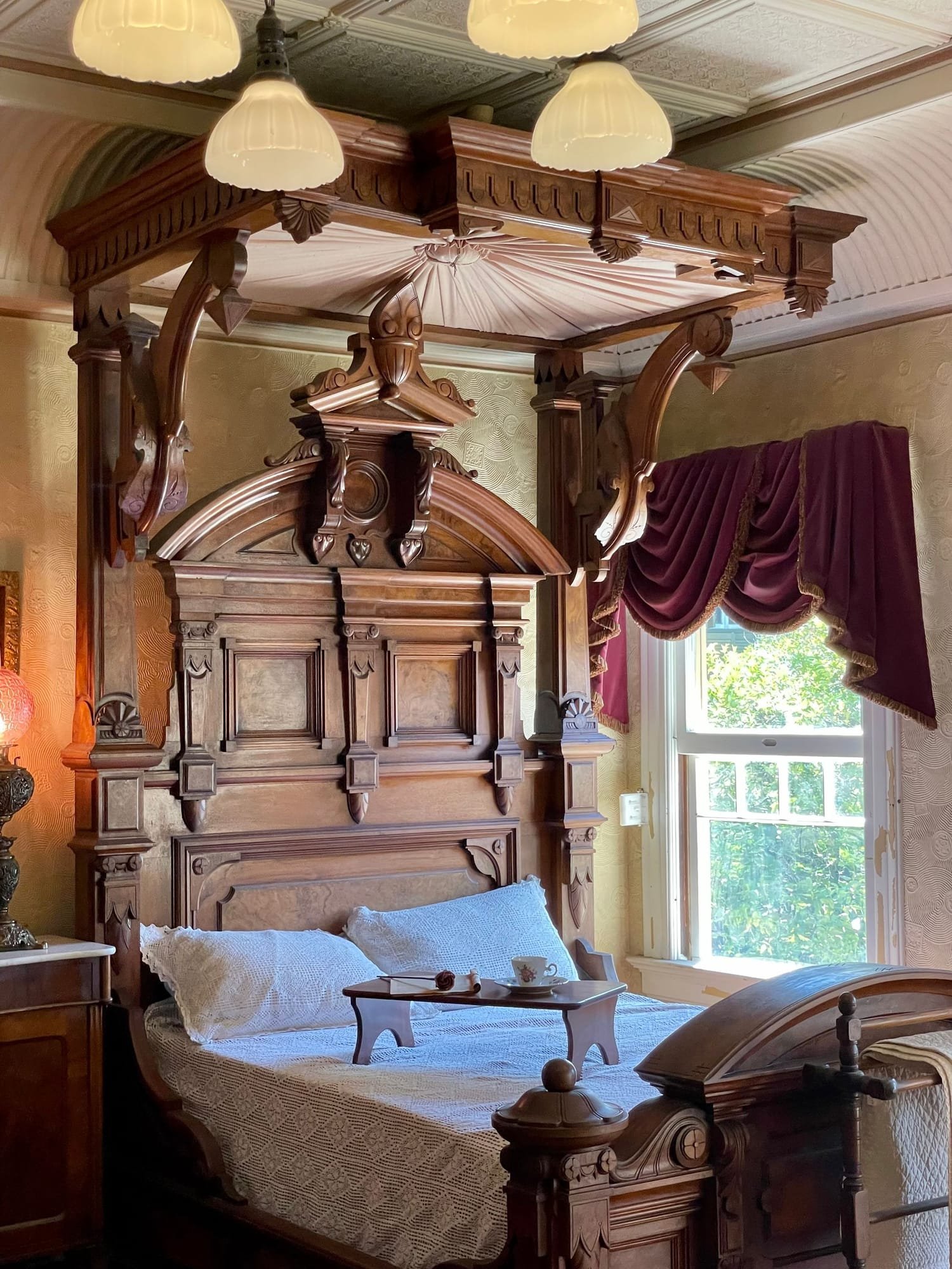 The Judge's Room in morning light: a carved walnut bed with a coffee tray, lace pillows and a tall window
