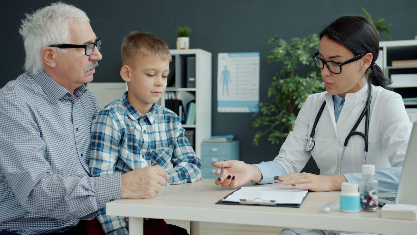 A grandfather and his grandson talk with Dr. Shah across her desk