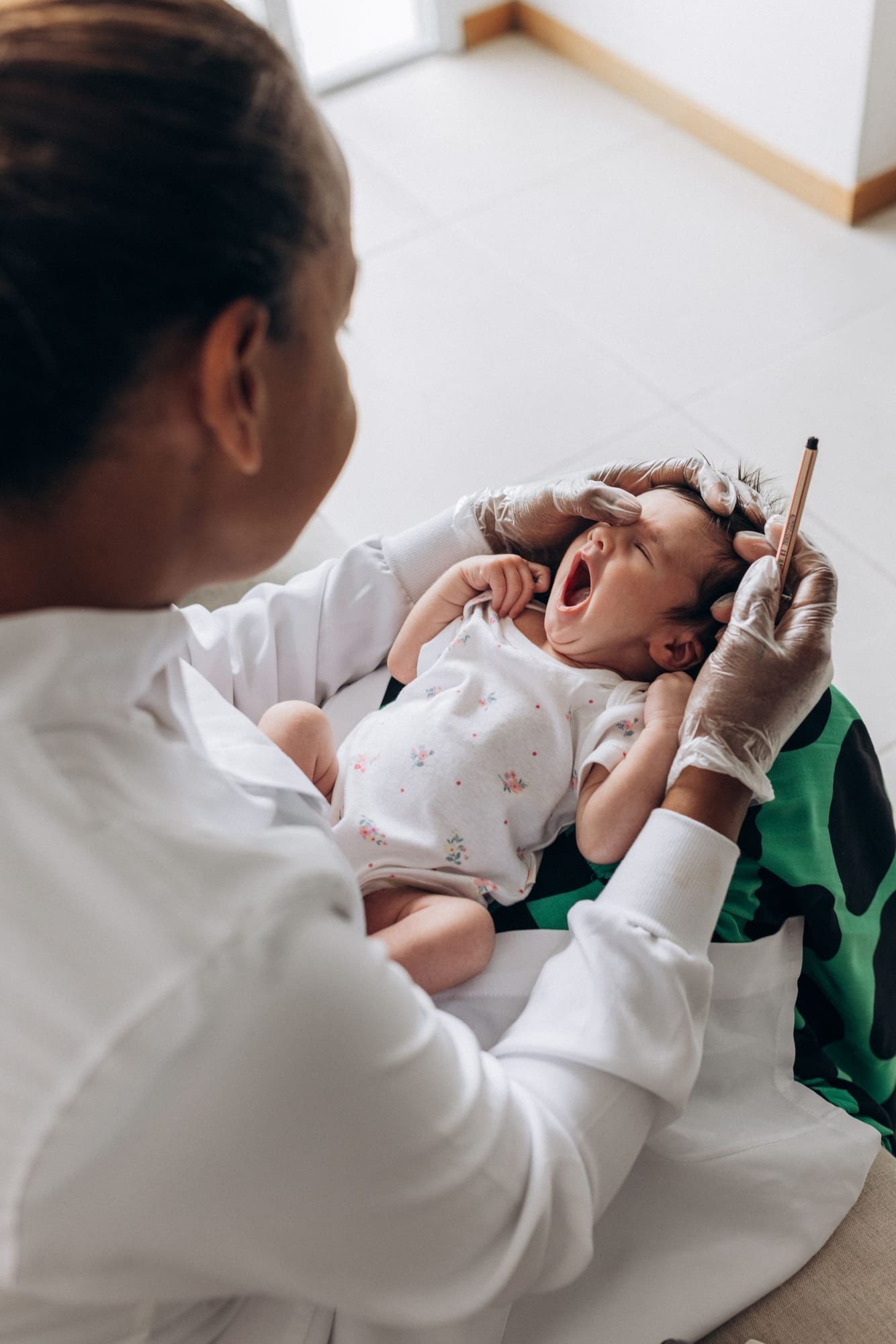 A doctor checks a yawning newborn on the exam table