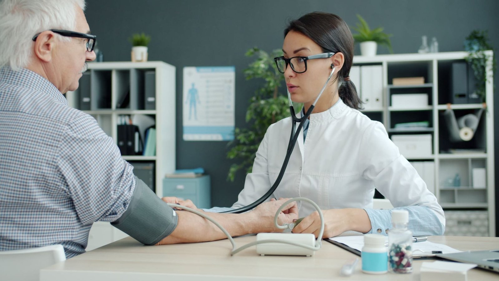 Dr. Shah takes an older man's blood pressure at her desk