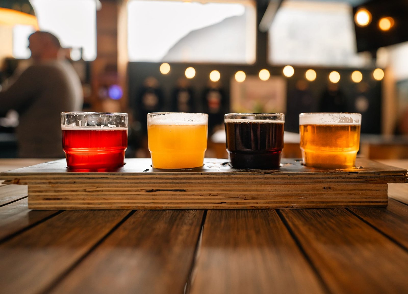 A flight of four beers on a wooden paddle, red, gold, dark and amber