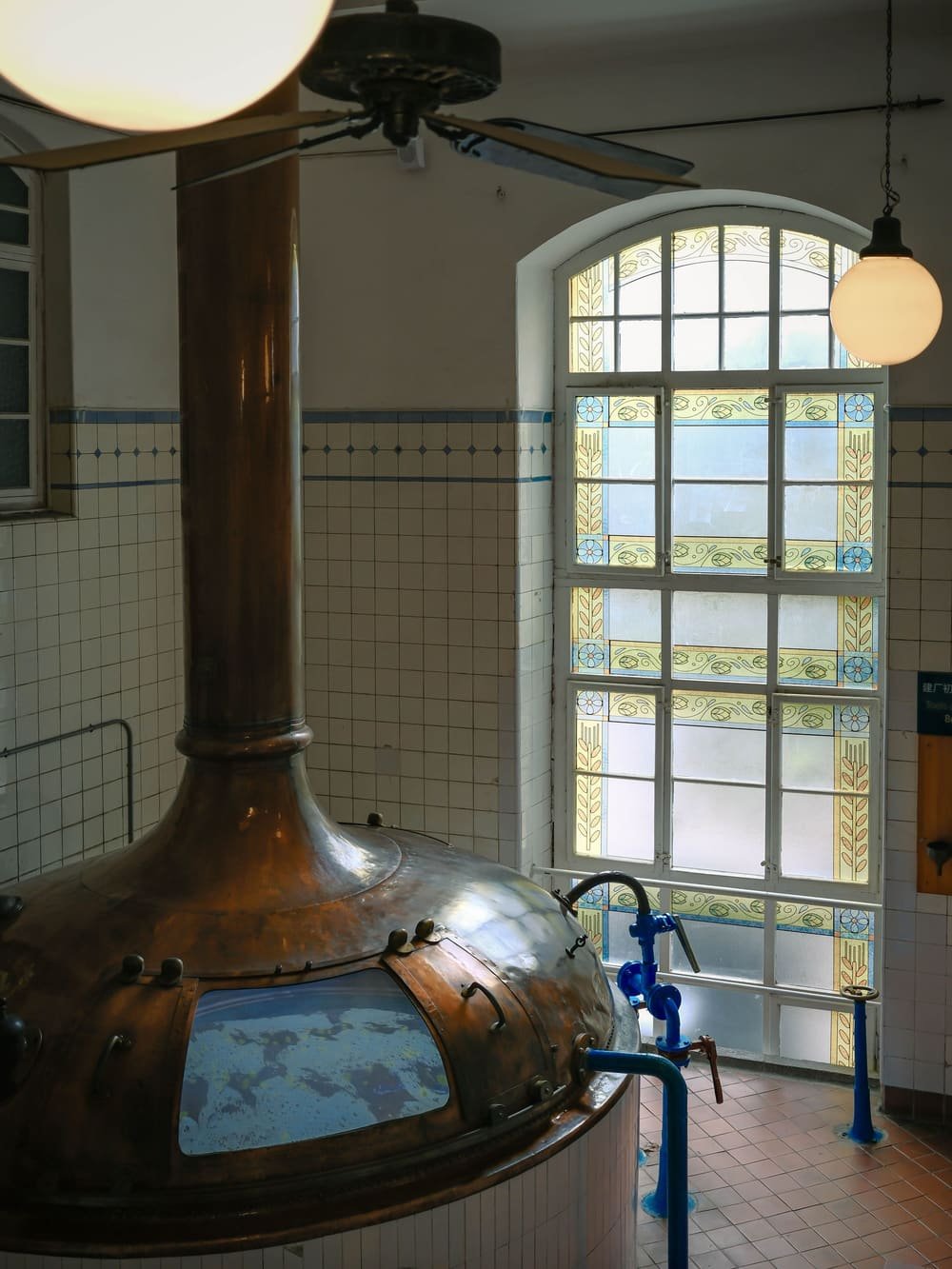 The copper brew kettle beside a tall arched window