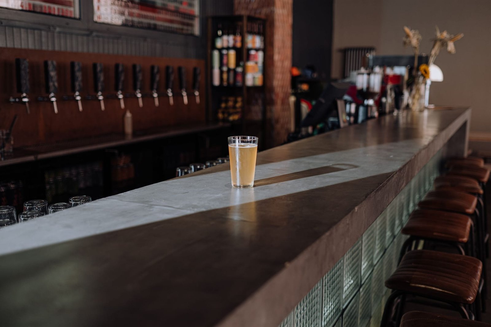 The long taproom bar with a full glass at the end and the tap wall behind it