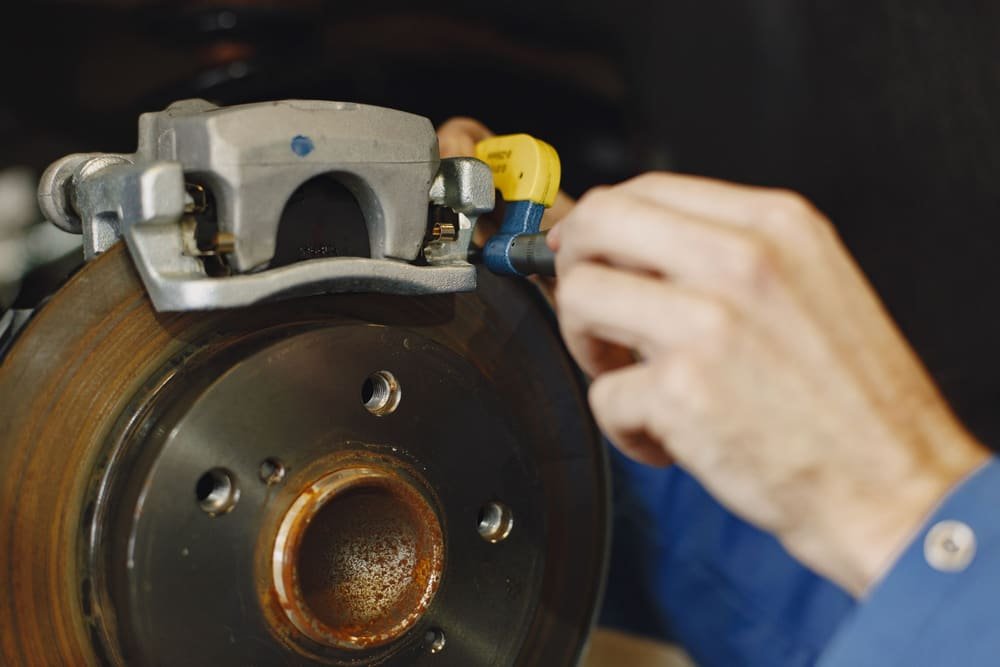 Hands fitting a brake caliper over a worn rotor