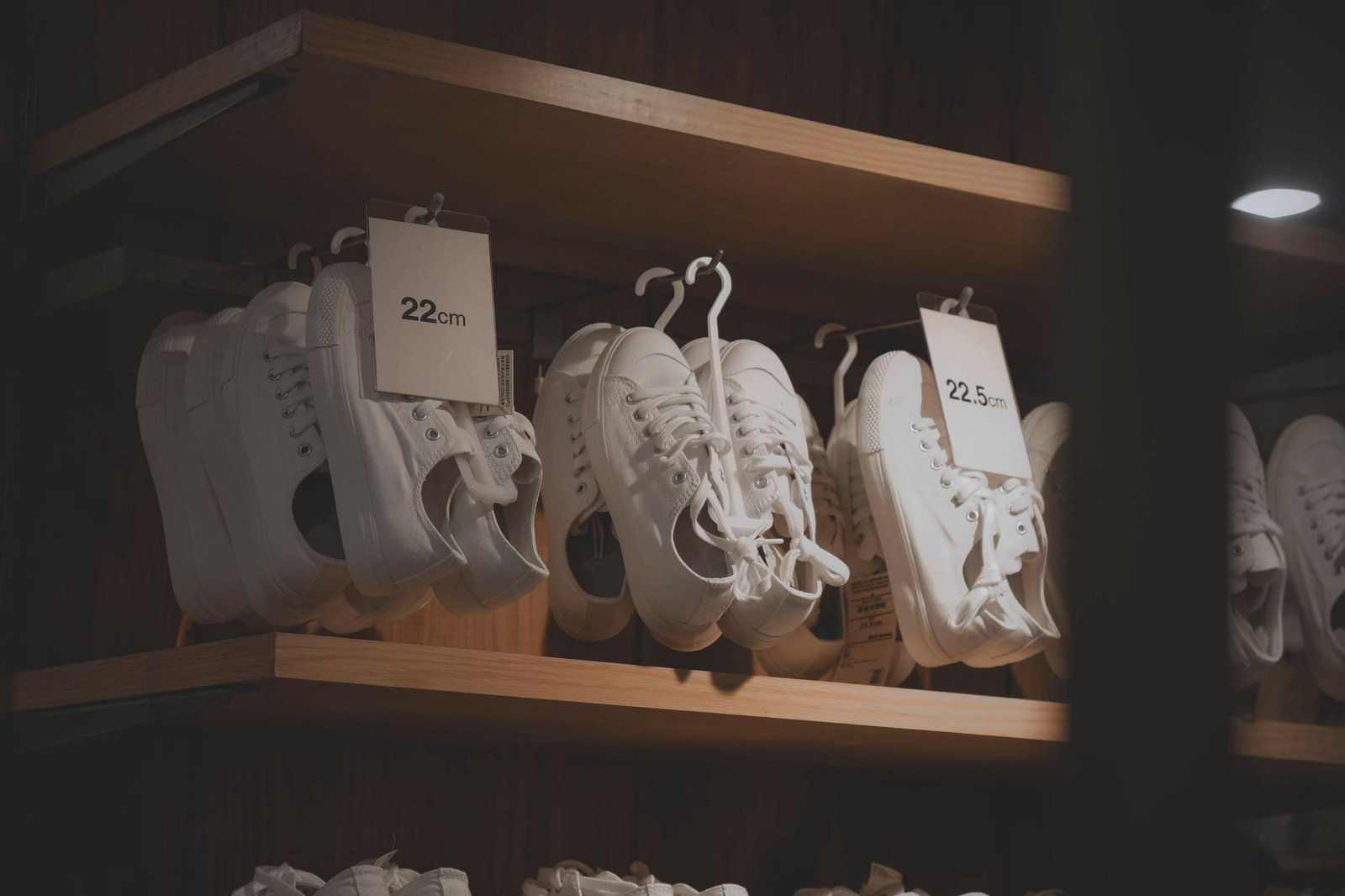 White sneakers hanging on the hold shelf with size tags clipped to them