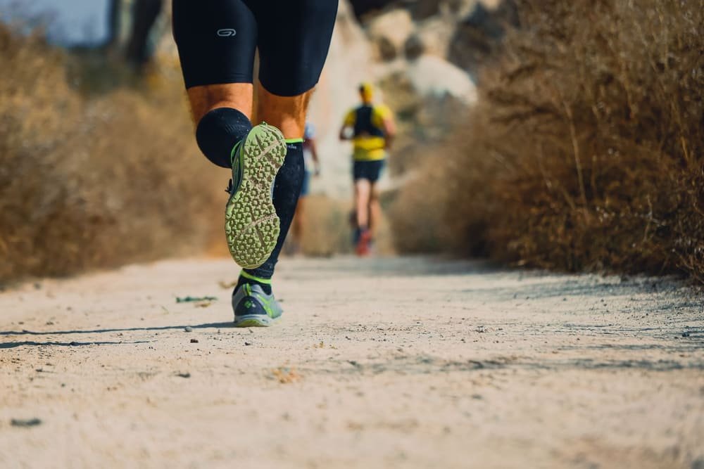 A runner on a dirt trail, one gray sole lifted toward the camera