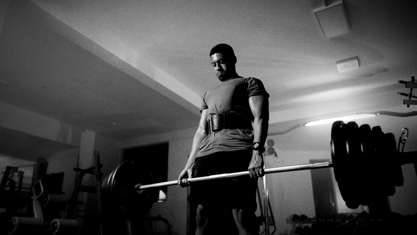 A lifter in a belt standing tall at the top of a heavy deadlift