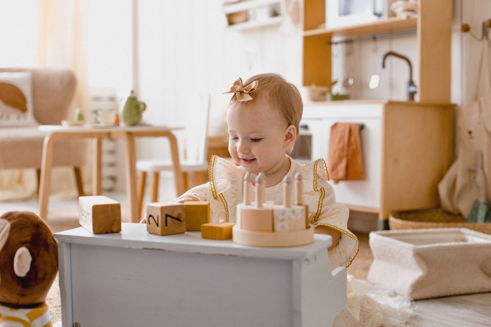 A baby sitting at a low shelf, playing with wooden stacking toys