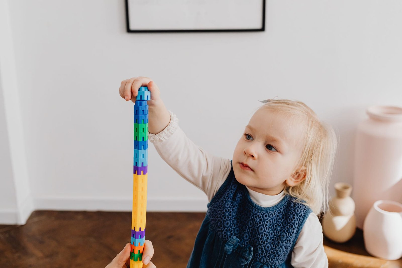 A toddler carefully adding a block to a tall tower