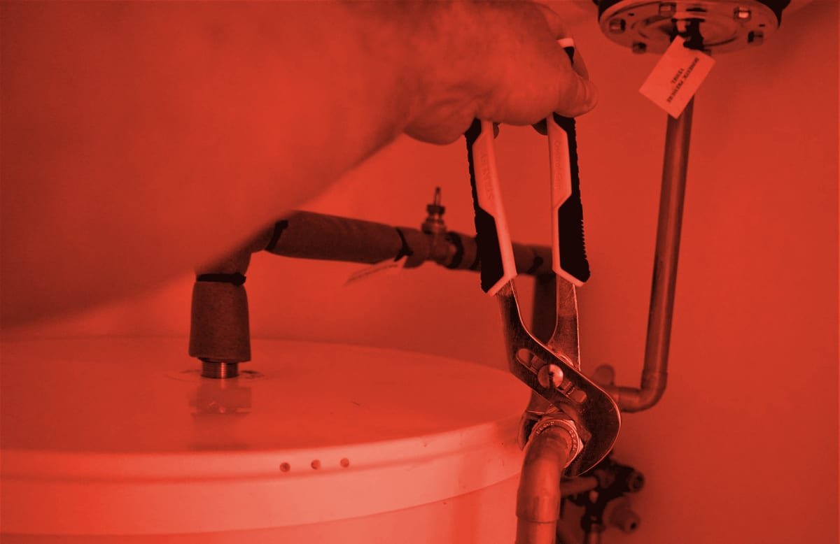 A plumber's wrench on the pipe fitting of a water heater