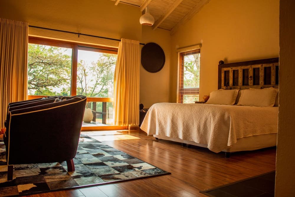 A Cedar Lodge room with a quilted bed, a reading chair and a window onto the trees