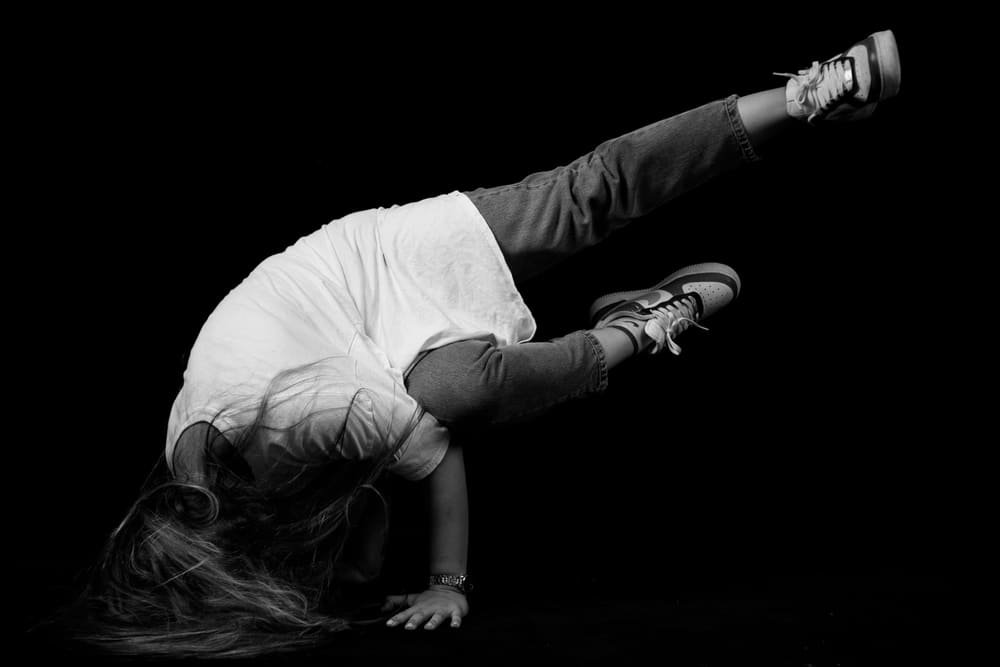 A young dancer holding a freeze on one hand, in black and white