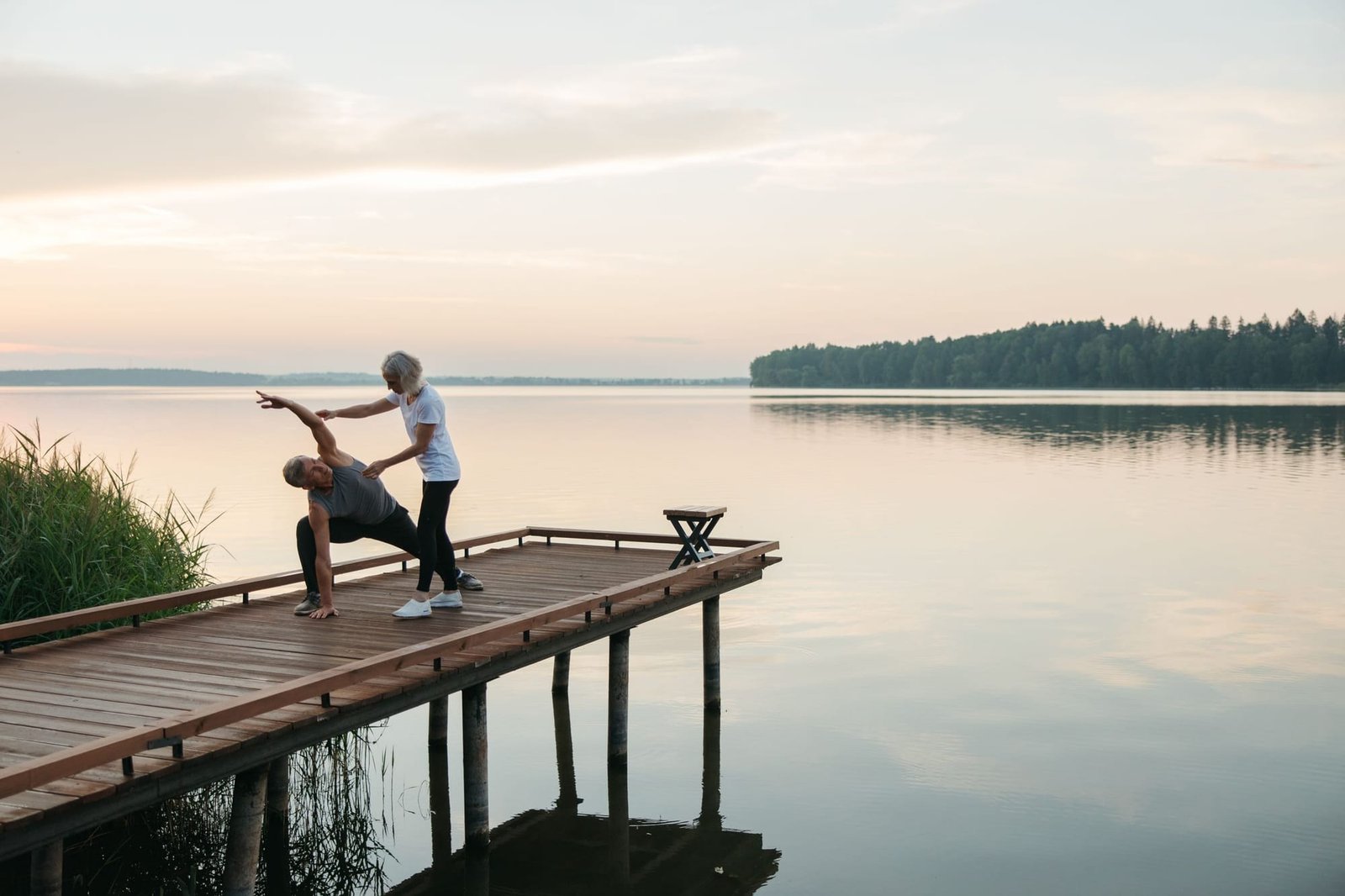 Two students on the wooden dock over the still lake at sunrise