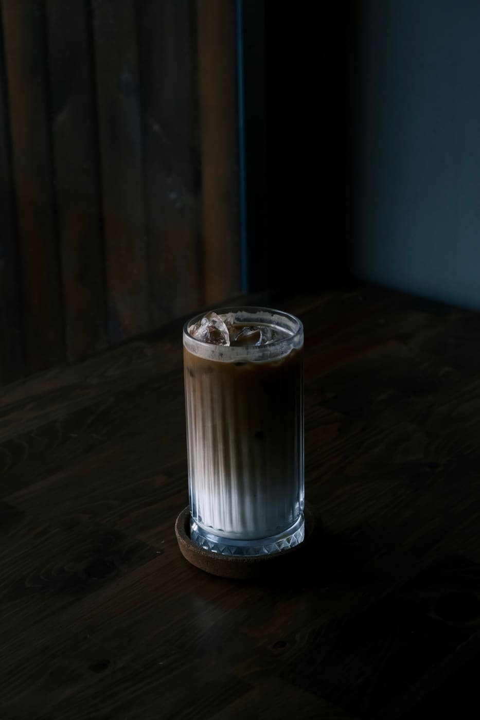A tall glass of iced coffee on a dark table
