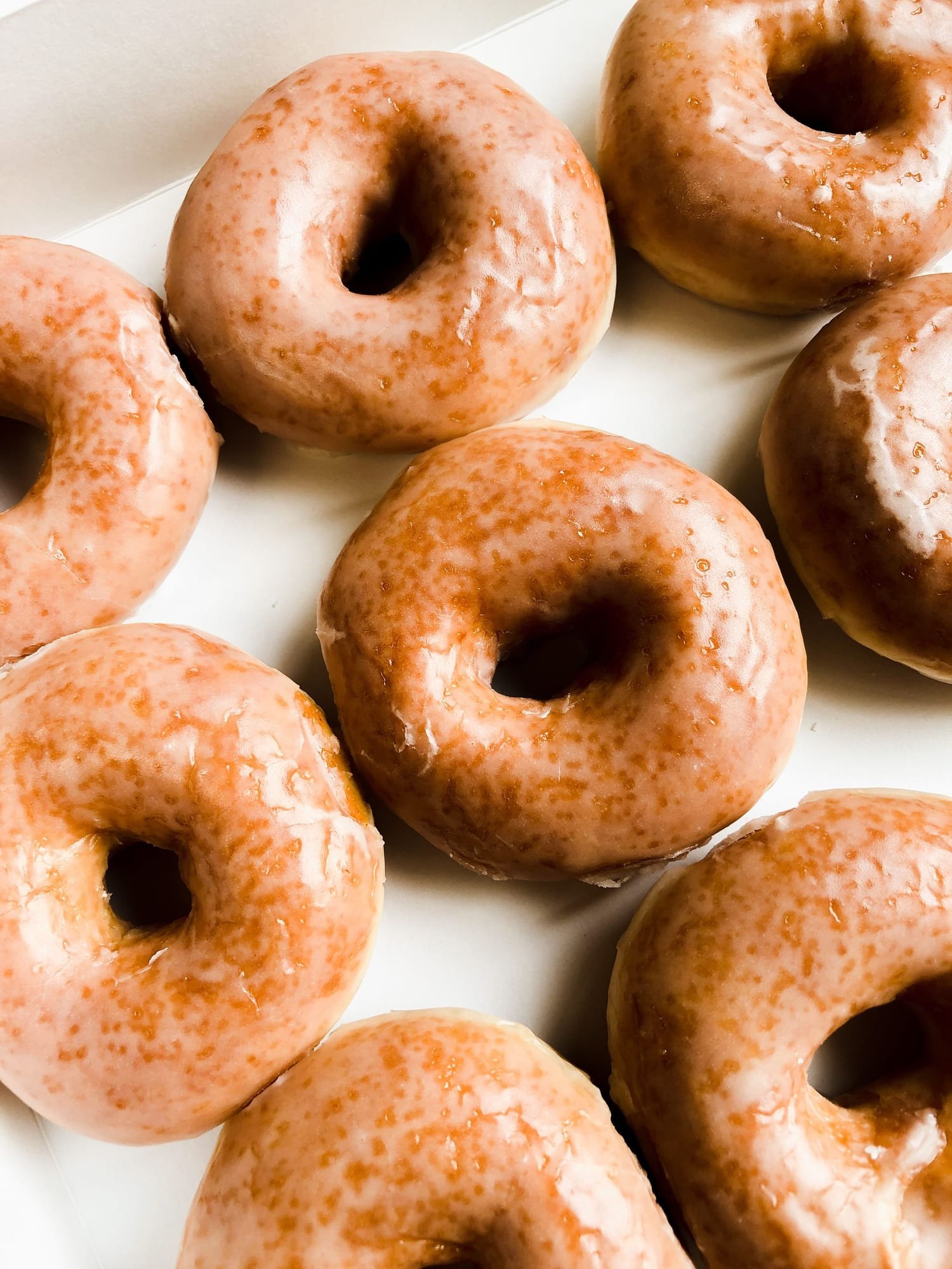 Rows of glazed donuts cooling on a tray